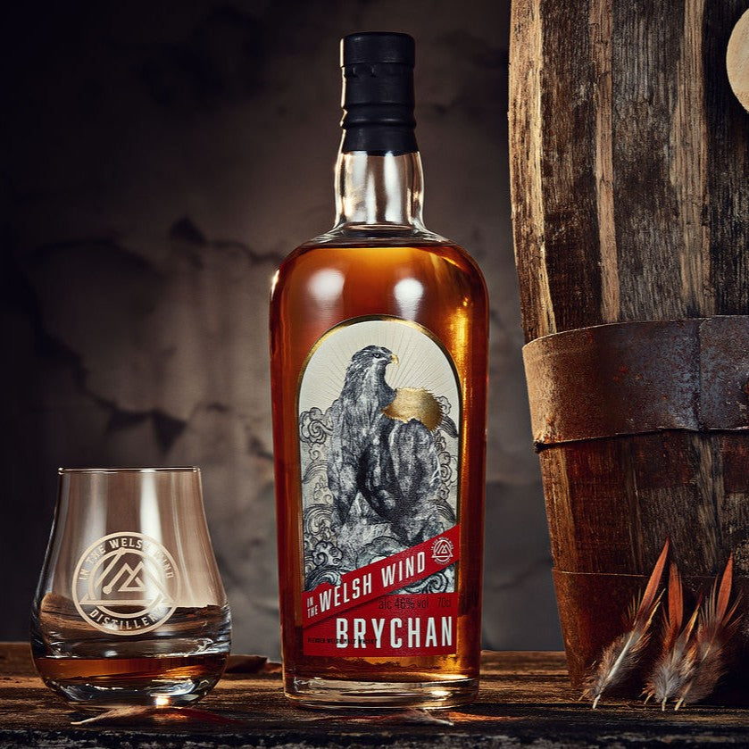 A bottle of In the Welsh Wind Brychan blended Welsh malt whisky with a glass on a cask