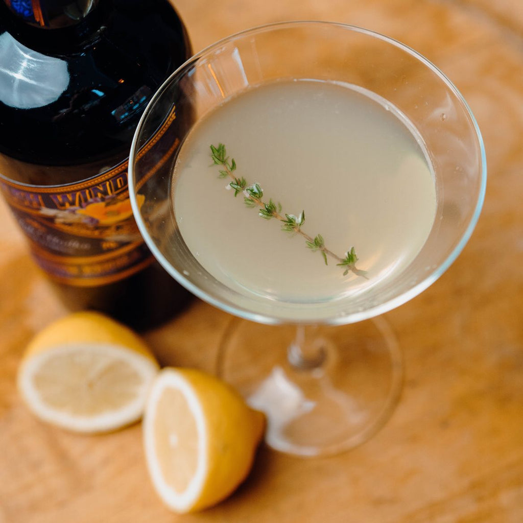 cocktail glass with cocktail and thyme sprig floating as garnish