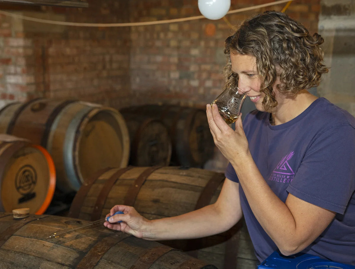 Ellen nosing a sample drawn from the cask among the barrels at In the Welsh Wind distillery